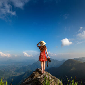 woman hand holding camera and standing on top of the rock in nat